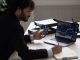 Smart focused Indian broker investor, stock trader using smartphone and laptop to analyze and invert in the financial market of cryptocurrencies, buy or sell crypto coins, planning strategy